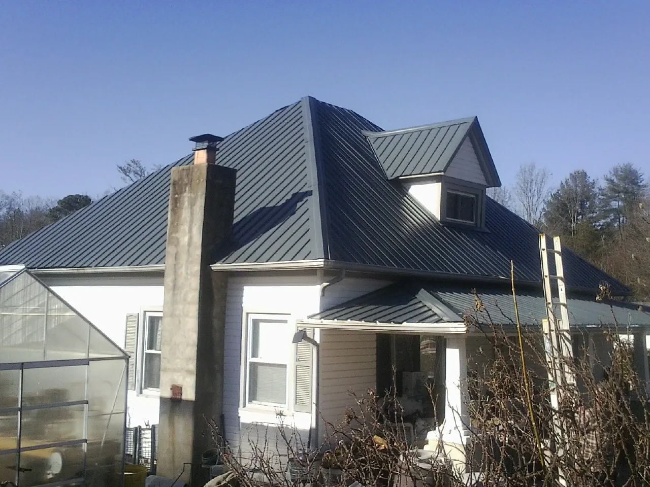 Dark blue standing seam metal roof on a white farmhouse with dormer — Slate & Tile Roof Repair by Roofing Brothers in Hamersville