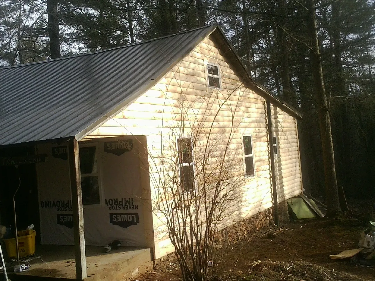 Log siding gable end under a dark metal roof edge in Hamersville