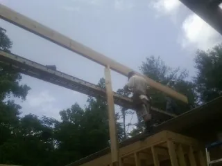 Carpenter setting a ridge beam over a new addition frame — Ice Dam Removal by Roofing Brothers in Hamersville