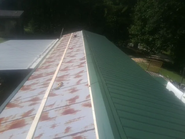 Old rusted panels beside newly installed green metal roofing — Wind Damage Roof Repair by Roofing Brothers in Hamersville