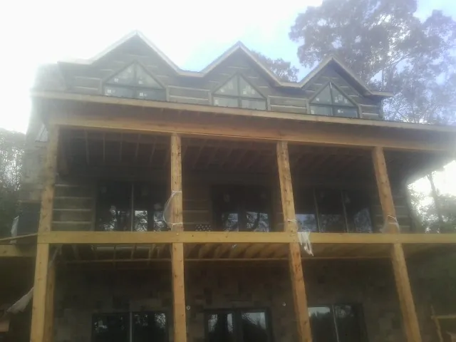 Dormers and porch framing on a large log home under construction — Roof Coating work by our crew in Hamersville