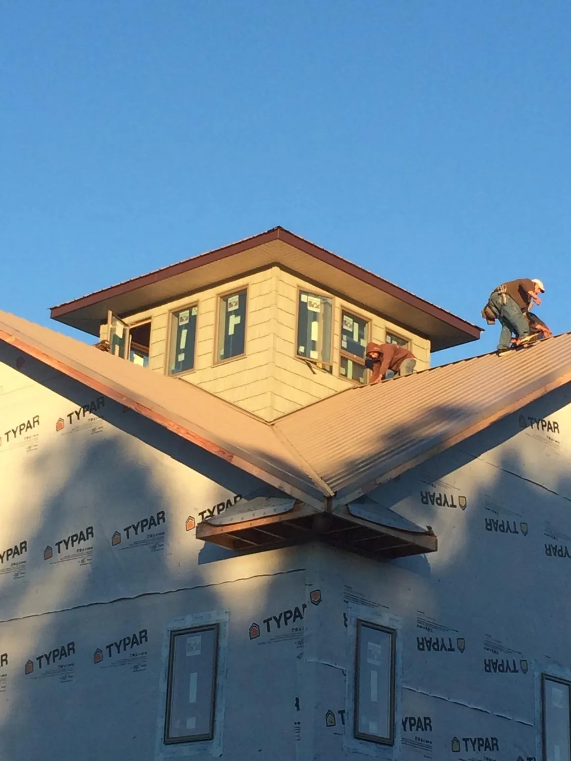 Roofers working around a rooftop cupola on a new metal roof at sunset — Roof Waterproofing in Hamersville by Roofing Brothers